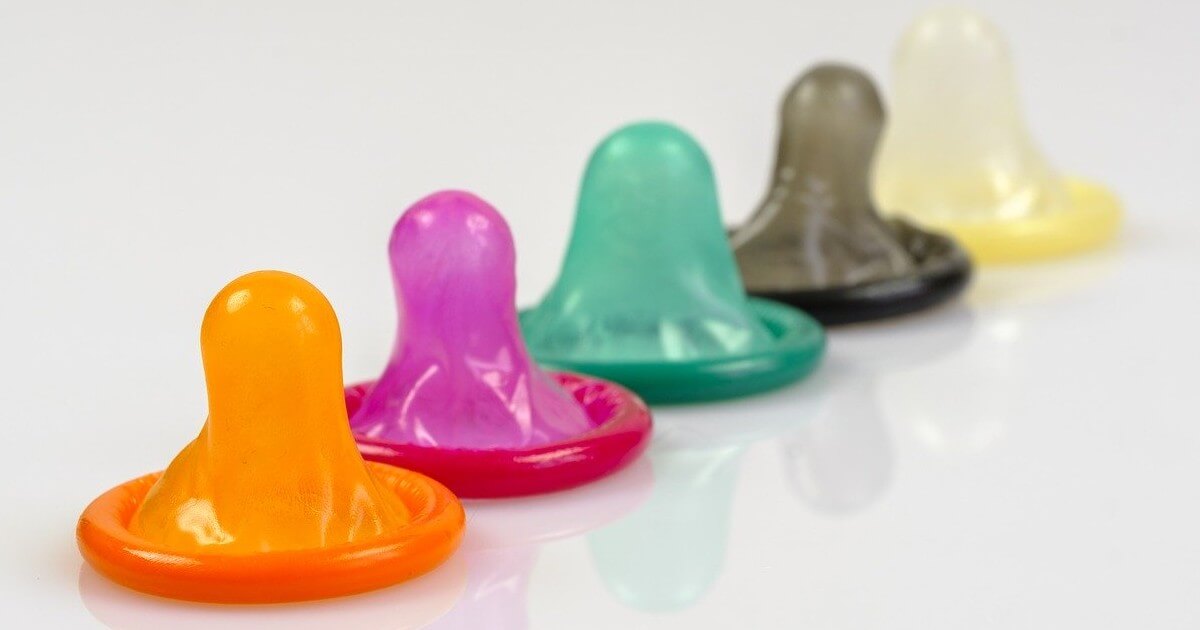 Five multicolored condoms appear in a row on a white background.