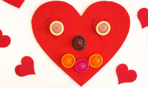 A red heart with a smiling face created with condoms.
