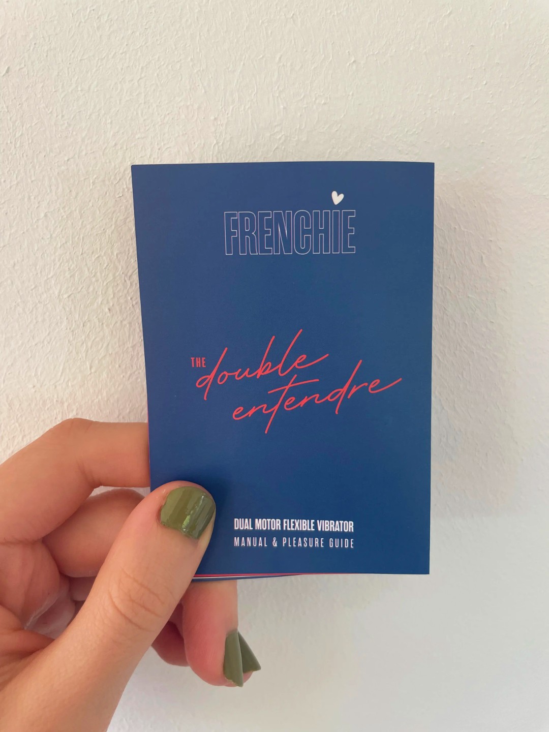 A hand holds the cove of the manual for Frenchie's The Double Entendre bendable vibrator.